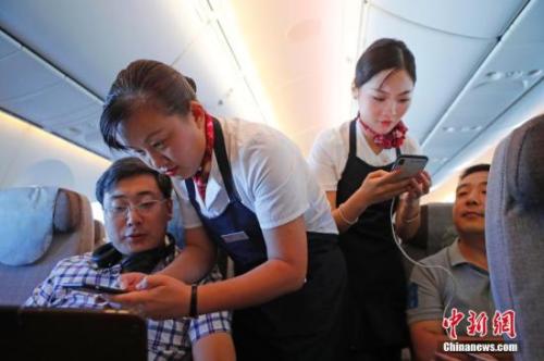 資料圖：乘務(wù)員們在客艙內(nèi)為旅客調(diào)試機上上網(wǎng)功能。<a target='_blank' ><p  align=