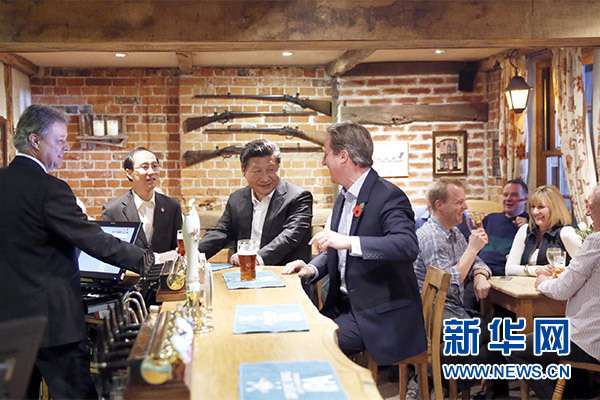 這是會晤結(jié)束后，習近平在卡梅倫陪同下乘車前往當?shù)匦℃?zhèn)體驗酒吧文化。新華社記者 鞠鵬 攝
