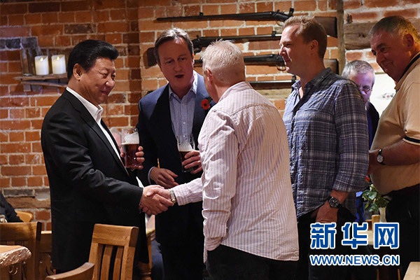 這是習近平與卡梅倫飲啤酒，并同當?shù)孛癖娊徽?。新華社記者 饒愛民 攝